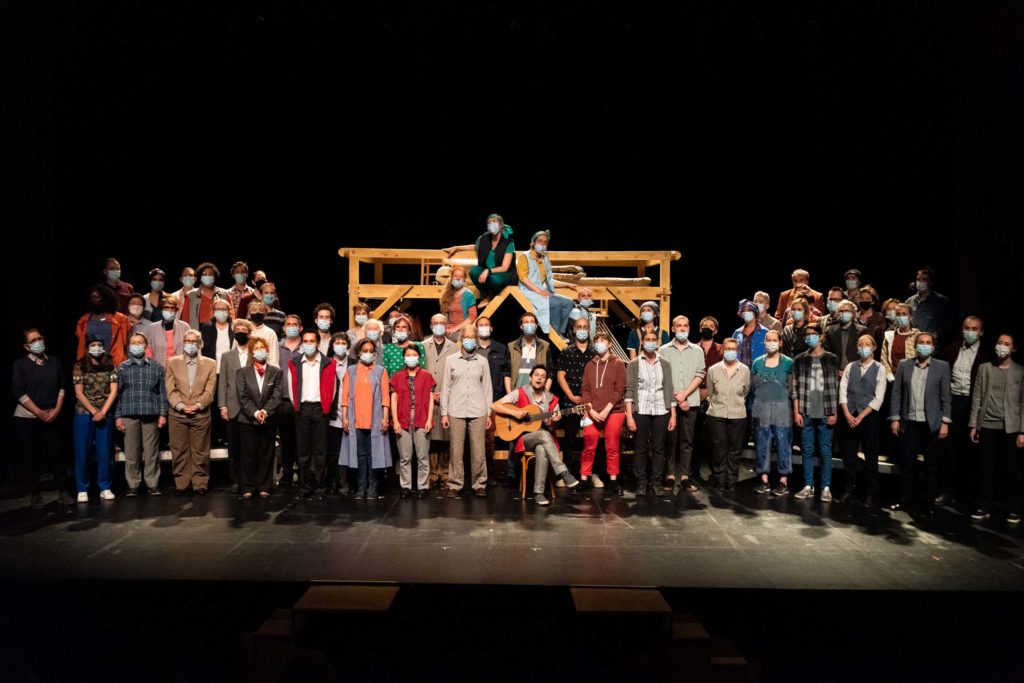Groupe d'amateurs sur une scène de théâtre. Tous portent un masque chirurgical
