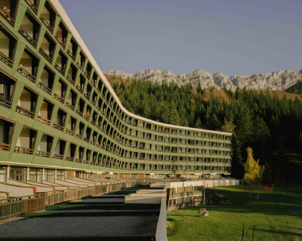 Photo de la Villa Glovettes. Immeuble de couleur verte incrusté dans un paysage de montagnes.