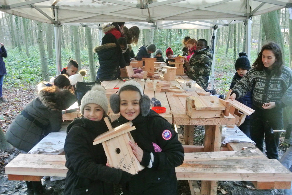 Enfants participant à un atelier bois, dans une forêt.