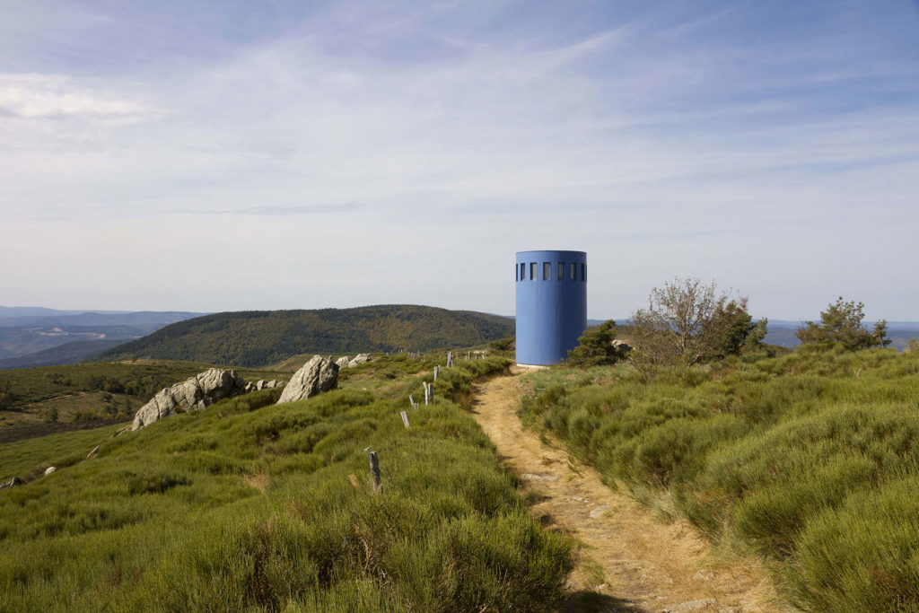 Une phare bleu posé dans un paysage de verdure.